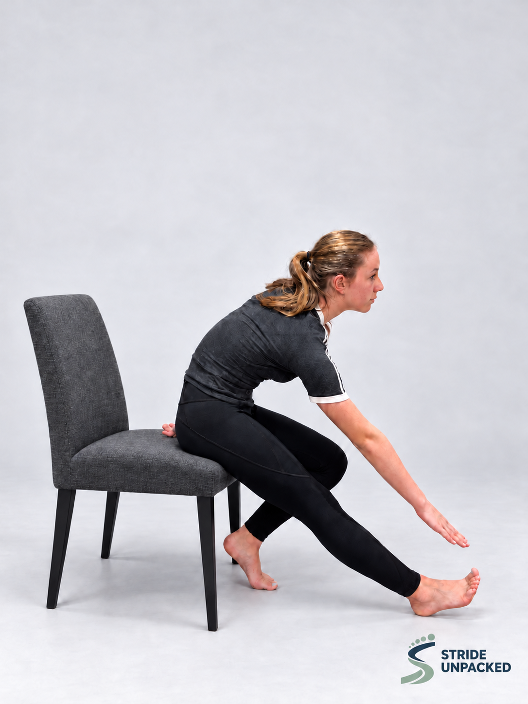 Person seated on a chair with one leg extended and heel on the floor, leaning forwards for a hamstring stretch.