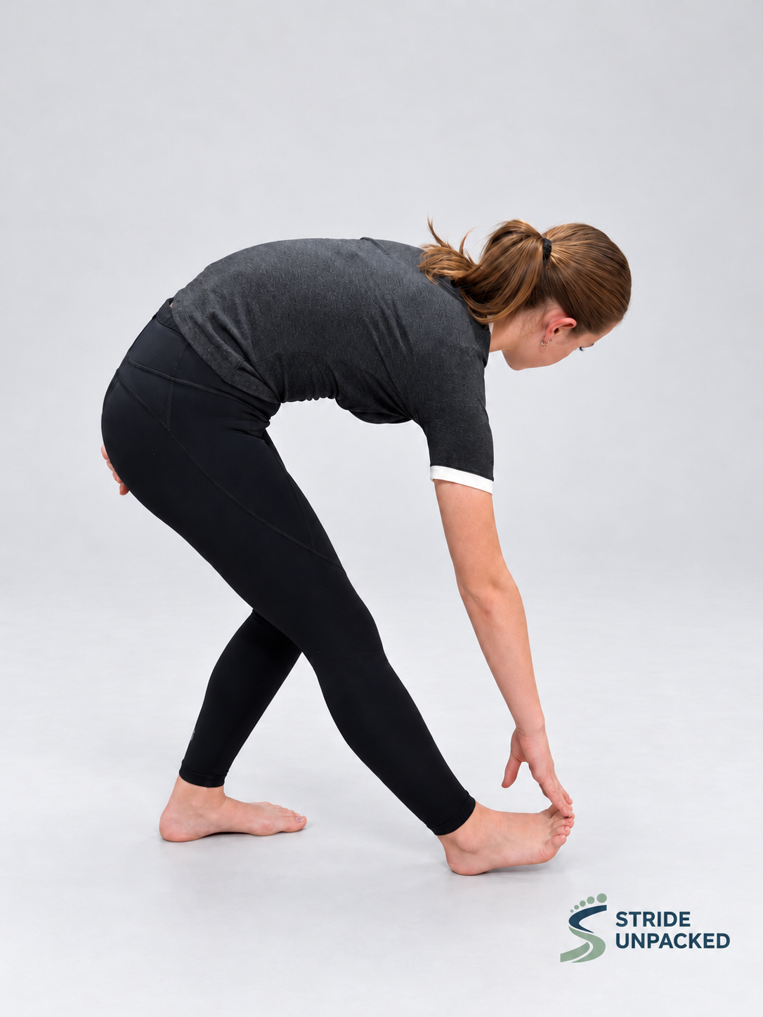 Person demonstrating a standing hamstring stretch with one leg extended forwards, heel grounded and torso leaning forwards.