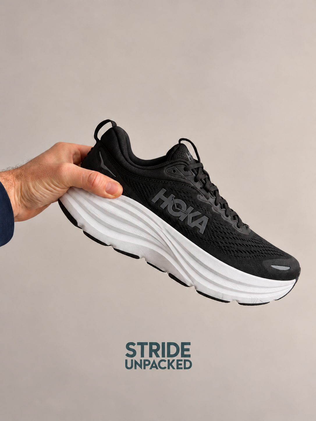 Hand holding a black HOKA Bondi 9 trainer with a white sole and Stride Unpacked watermark.